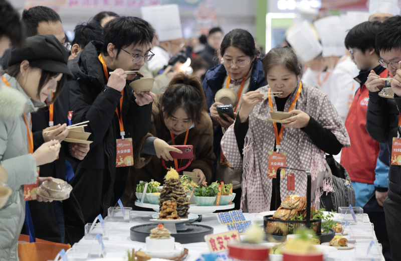 2026年1月31日，游客在江苏南京美食嘉年华凉菜区品尝、拍照。新华社发（刘臻睿摄）
