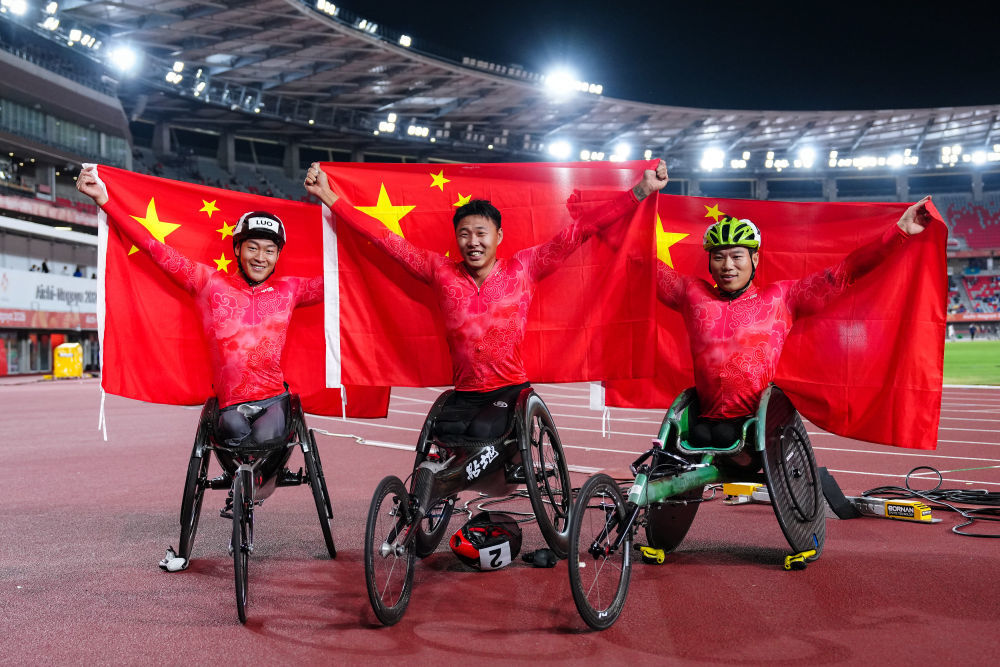 10月23日,中国选手金华(中)、罗兴传(左)、代云强在男子5000米T54级比赛后庆祝胜利。他们分获冠、亚、季军。新华社记者 贾浩成 摄