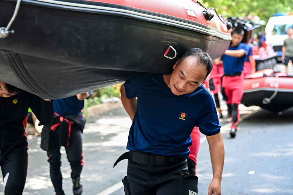 ↑ 7月10日,在广西贵港市救援一线,来自广西桂林市消防救援局的党员杨东升与战友一起将橡皮艇扛至预定水域。