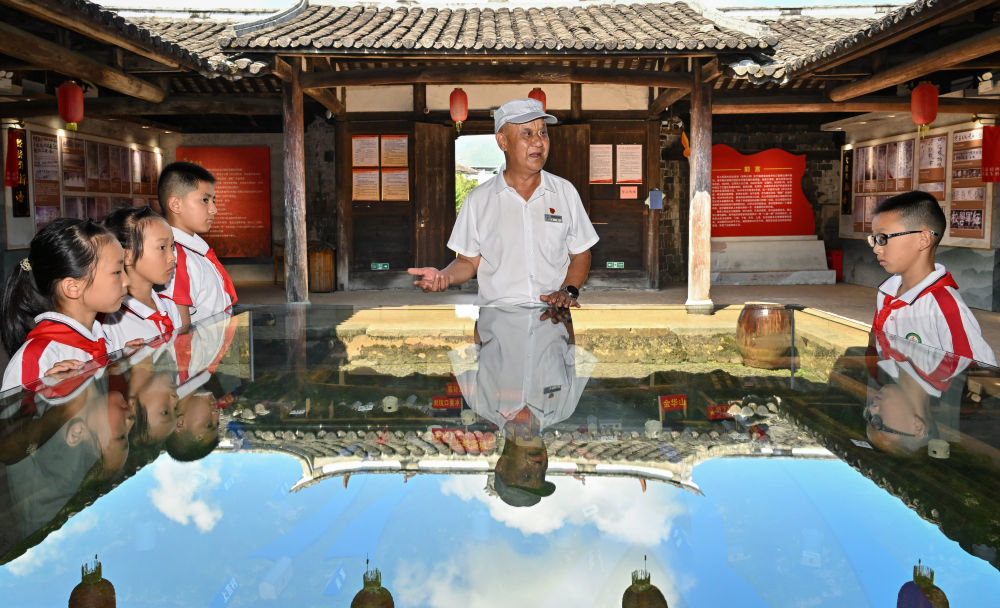 2026年7月24日，红军烈士后代、村里的红色讲解员钟鸣在中复村观寿公祠内为参加红色研学活动的小学生讲解。新华社记者 韩旭 摄