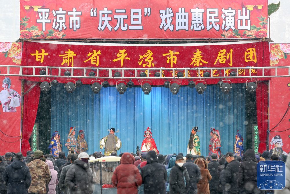 ↑ 1月2日,在甘肃省平凉市崆峒区,人们冒雪观看戏曲惠民演出。新华社发(吴希会摄)