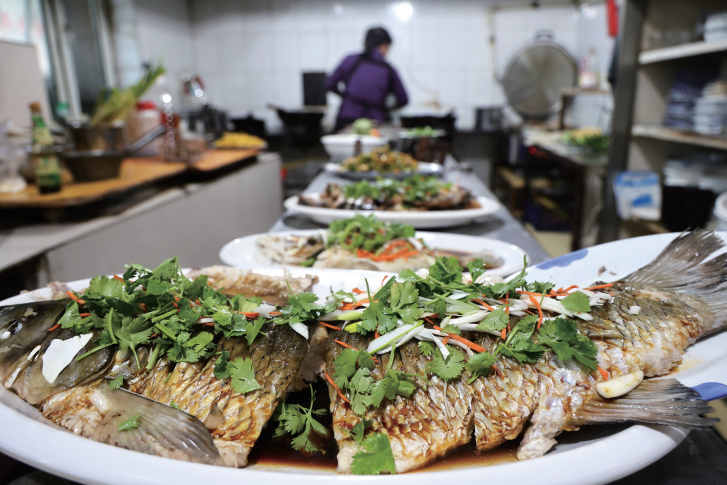 2025年11月22日，查干湖畔一家农家乐的厨师烹制查干湖鱼。当地通过政策引导与资源整合，打造“住民宿、品鱼宴、穿花袄”文旅新场景，推出“乡厨乡味”美食大赛、查小鱼音乐节、体育健身运动展演等活动，延展冰雪旅游产业链，助力乡村振兴。2025年5月1日，查干湖接待游客近7万人次，实现旅游综合收入6076.58万元，同比增长30%。