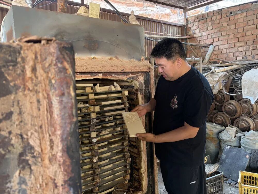 强安兴正在查看青砖工艺品的情况　新华社记者　程楠　摄