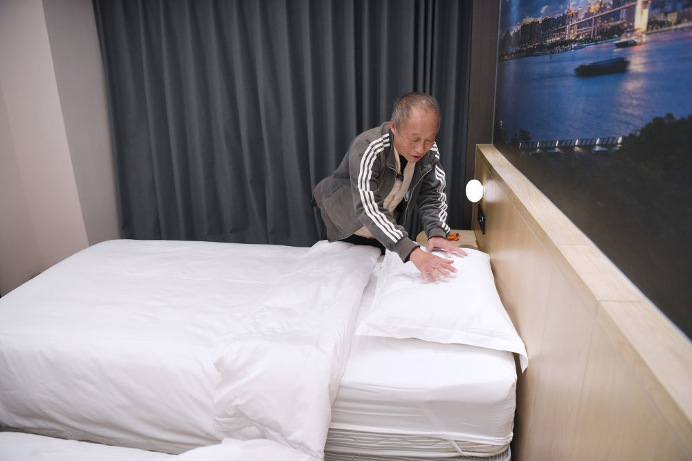 2025年11月28日，宏福苑居民邝佩麟在粤海酒店“爱心客房”里整理床铺。新华社记者 陈铎 摄