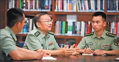国防科技大学计算机学院研究员王戟（中）在图书馆与学生讨论（2026年5月20日摄）。范军威摄（新华社发）