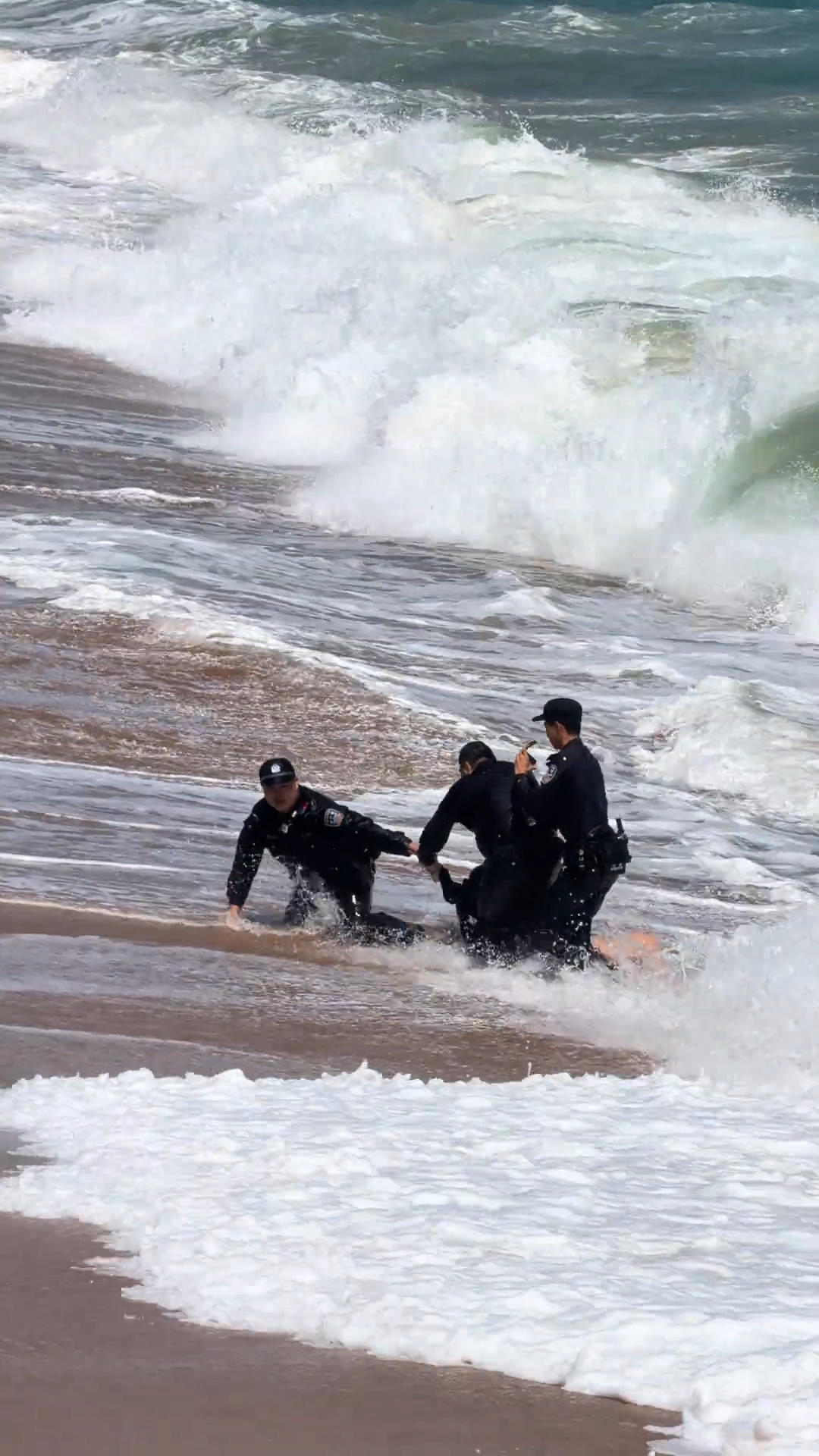 ▲三名警员合力将游客拖回岸边