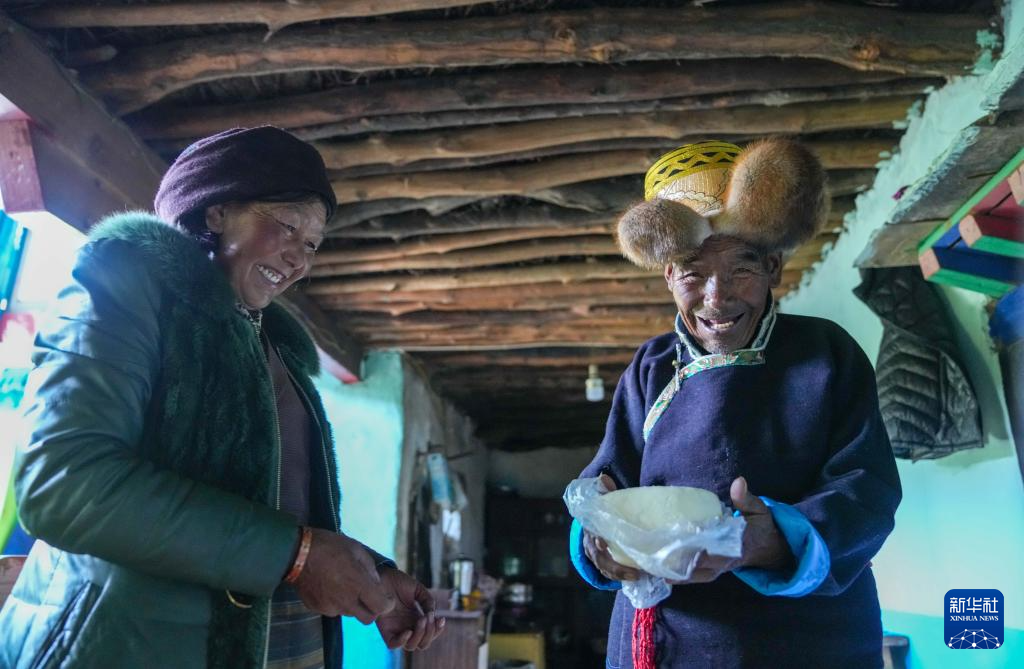 白玛扎西（右）从冰柜中取出准备做茶用的酥油（3月26日摄）。