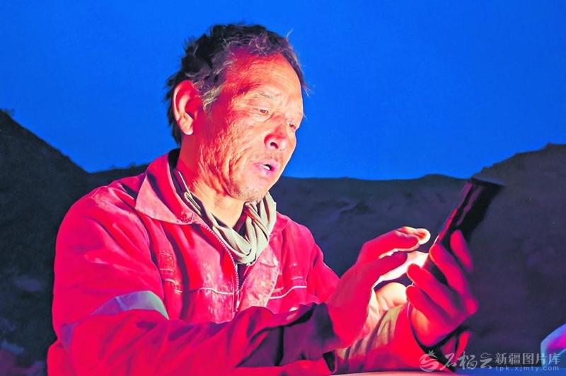 4月20日，吐西三维地震采集项目现场，工人魏正春完成当天的钻井任务后通过手机上报数据。