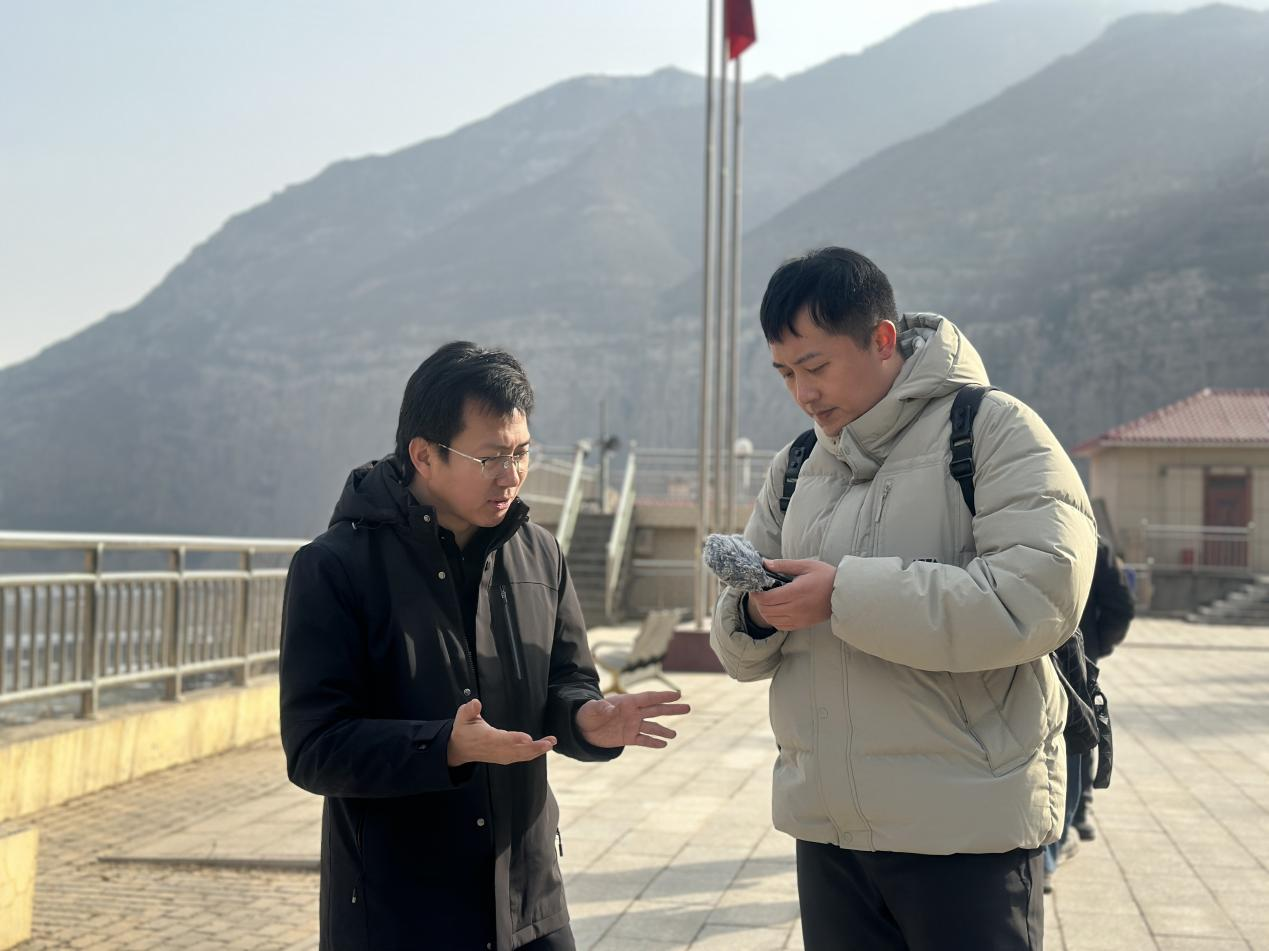 站长李超华(左)在站前广场跟记者讲述水文人“传帮带”的故事