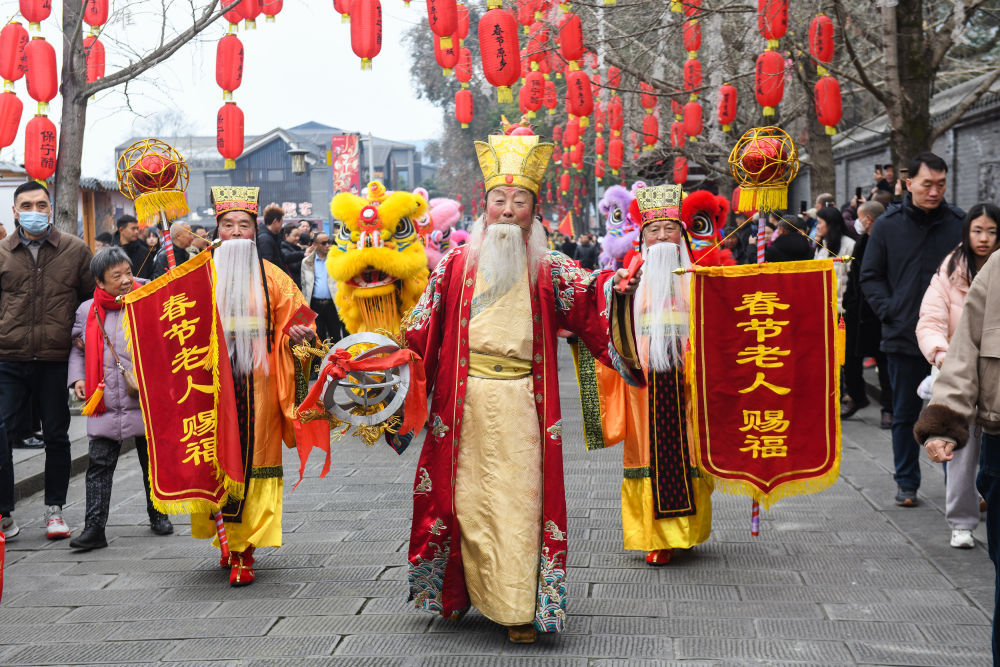 2月17日,在四川省阆中市,“春节老人”在阆中古城大街上给游客拜年。新华社发(王玉贵摄)