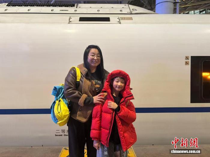 2月13日，肖晓旭和儿子在车站，母子二人仅携带少量随身背包。中新社记者 王梦瑶 摄