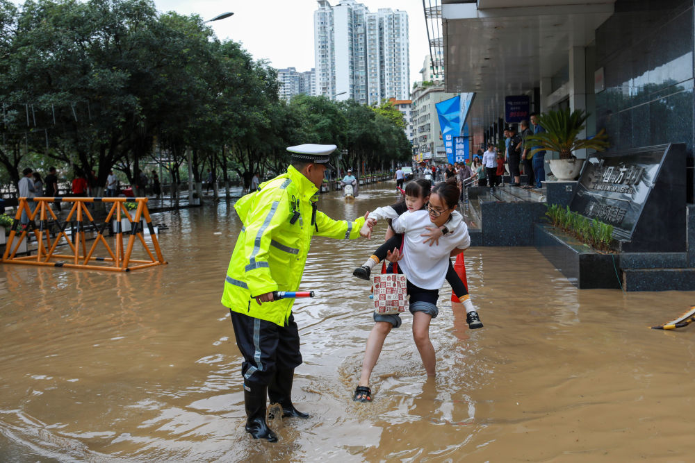 2026年5月19日,在贵州省都匀市一处积水的街道,交警帮助群众安全通行。5月18日6时至19日6时,贵州省都匀市遭遇特大暴雨。新华社发(肖伟 摄)