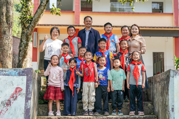 2026年3月30日,云南省文山壮族苗族自治州广南县莲城镇落松地小学教师农加贵(后排左三)、杨素芹(后排右一)、朱丽丹(后排左一)和学生在校园内合影。新华社记者 彭奕凯 摄
