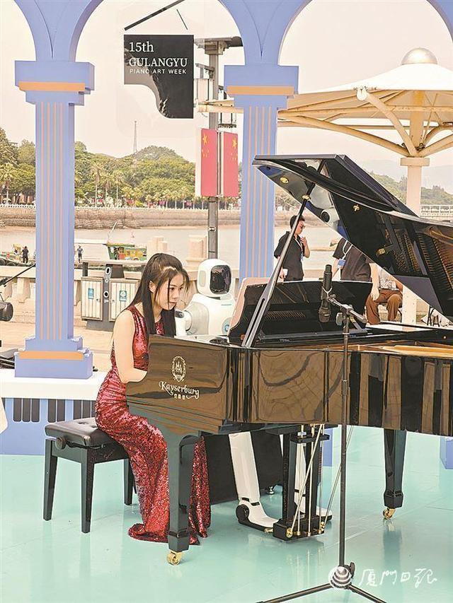 在鼓浪屿钢琴码头下沉广场,钢琴演奏机器人与钢琴演奏者一同登台,四手联弹《青花瓷》。