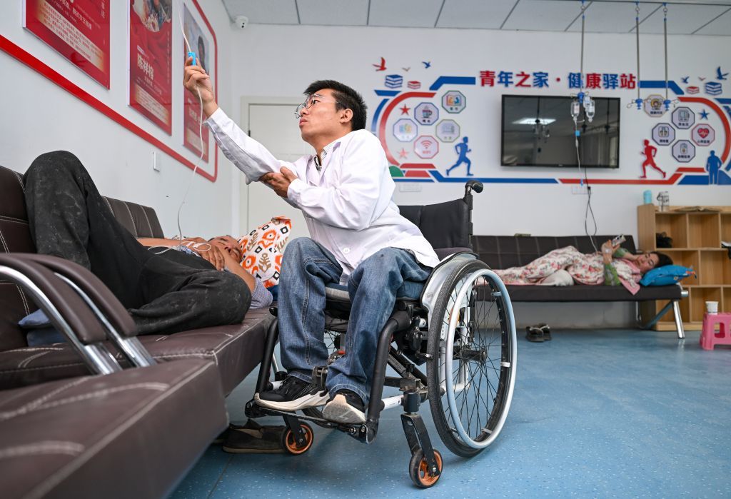 2026年7月27日，在新疆莎车县白什坎特镇，李创业在诊所内为患者检查输液情况。