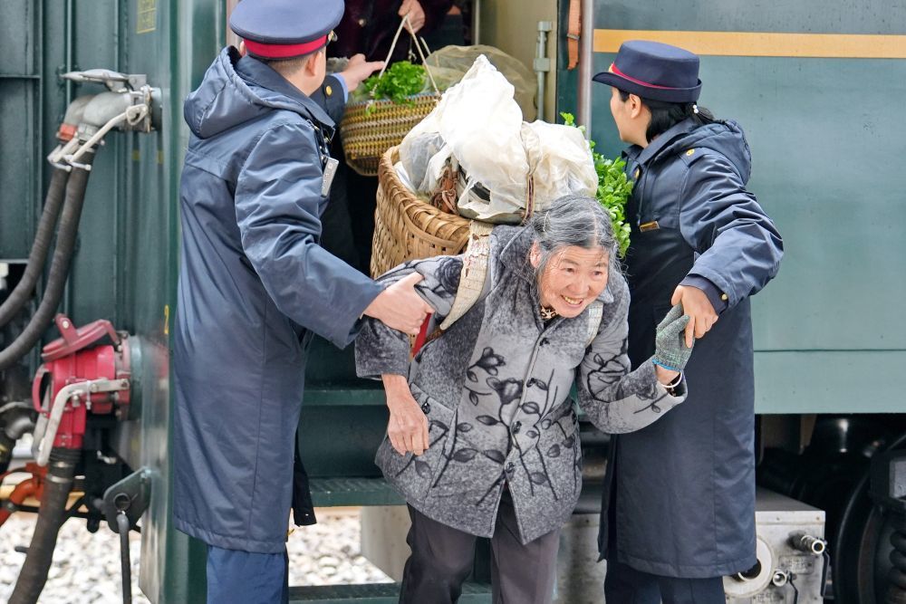 2026年2月25日，在遵义市，5630次列车到达桐梓站后，铁路工作人员协助村民下车。新华社发（张维 摄）
