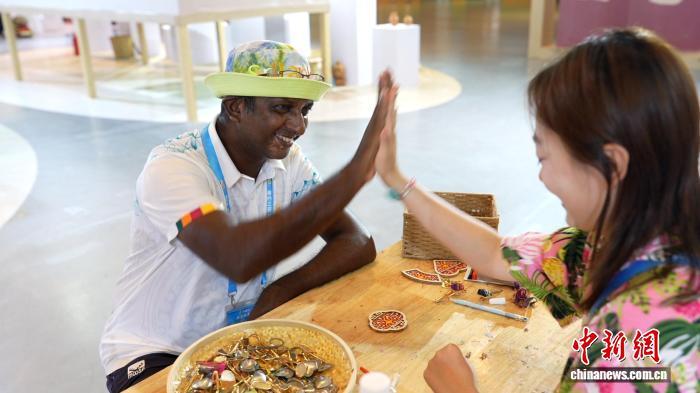 外籍运动员在体验黎锦文创制作后，与工作人员击掌。　陈英清 摄