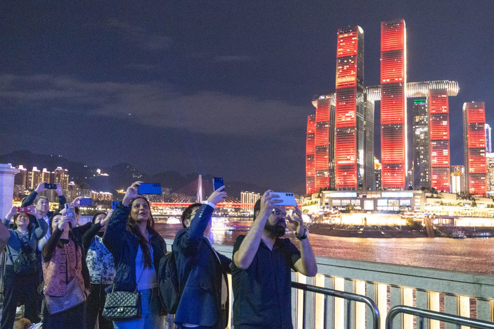 ↑ 4月22日，外籍游客在重庆市南岸区南滨路拍摄无人机灯光秀表演。