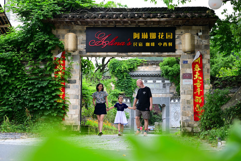 5月29日,阿琳娜(中)和父母在“阿琳娜花园”民宿内行走。 新华社记者 周牧 摄