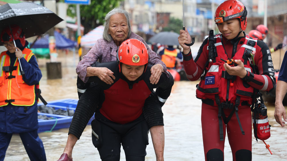 ↑ 7月8日,在广西钦州市钦南区那彭镇,救援人员帮助行动不便的群众转移至安全地点。新华社发(敖帅昌摄)