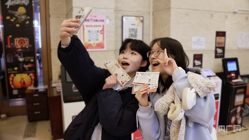 史好在亚洲大厦取票处与朋友合影(央广网记者 何智康 摄)