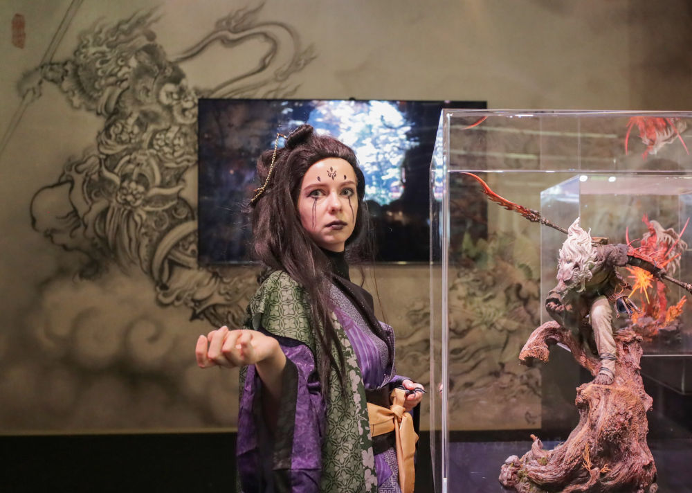 2025年8月20日，在德国科隆，一名《黑神话：悟空》游戏角色扮演者在游戏科学展台与模型合影。