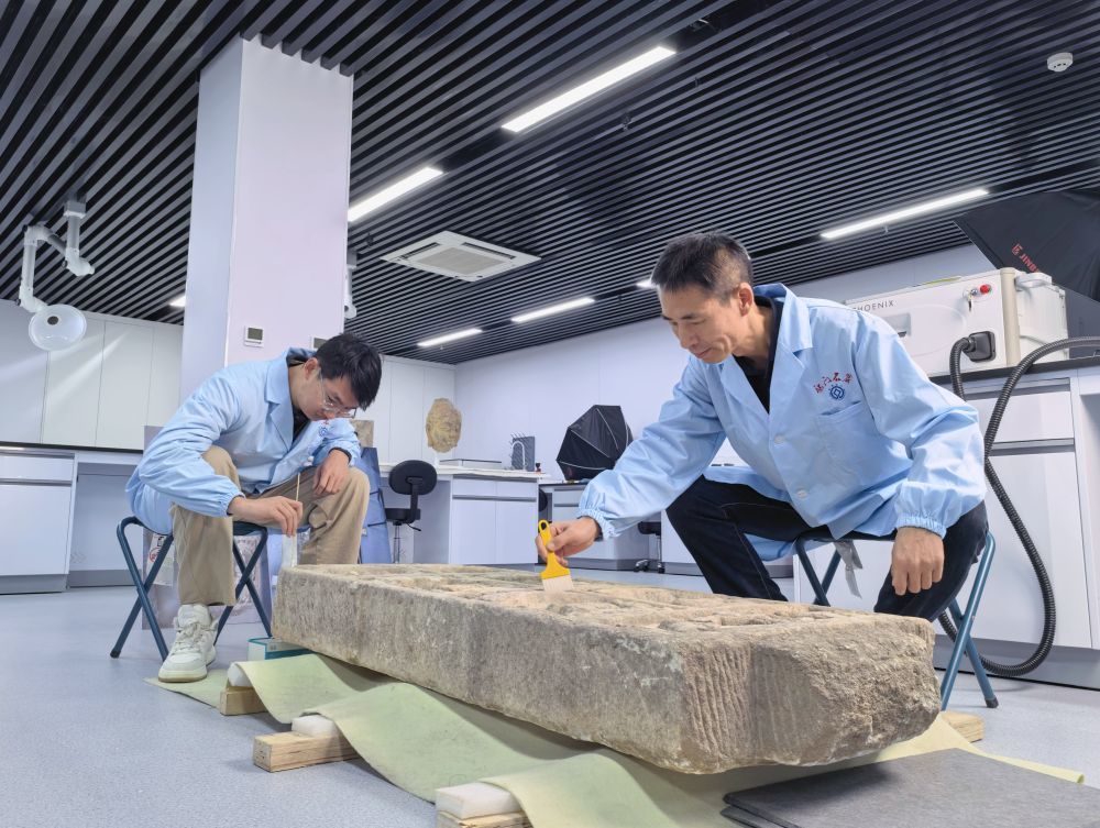 2025年12月31日,马朝龙(右)和同事正在清理一块北齐时期的造像碑。新华社记者 袁月明 摄