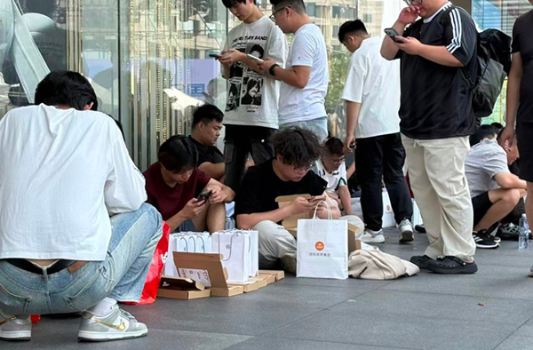 9月18日,黄牛在苹果店外收手机。