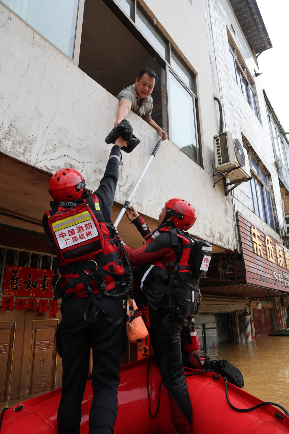 ↑ 7月8日,在广西钦州市钦南区那彭镇,救援人员沿街排查,为受困群众输送应急生活物资。新华社发(敖帅昌摄)