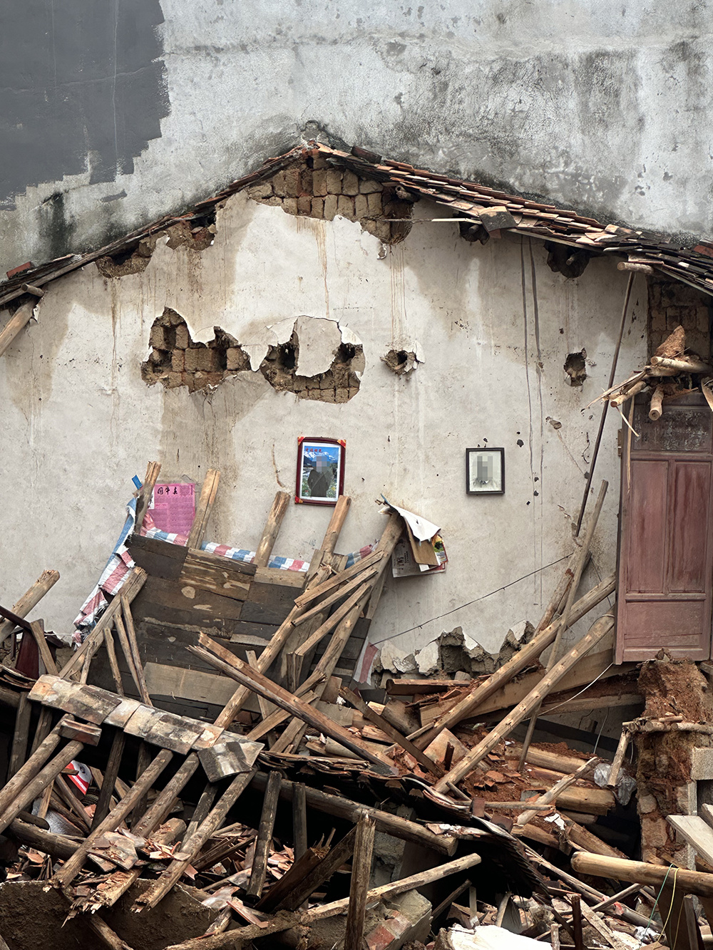 建筑体倒塌后，两幅装裱完好的人像依然端端正正地挂着。
