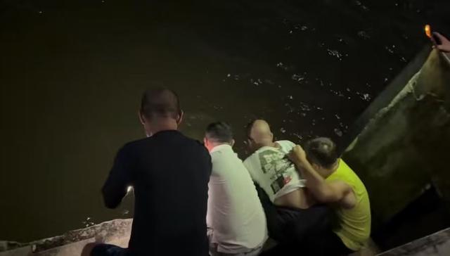 众人合力把落水者拉上岸。