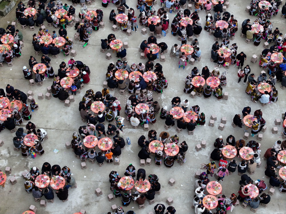 每年春节及春节前后，广西柳州市融水苗族自治县各乡镇村屯都会举办“坡会”，它是当地人交流感情、聚会娱乐的民间节日。每当坡会时，周边寨子男女老少身着节日盛装聚众集会，也吸引众多游客慕名而来，带动当地文旅产业发展。这是2026年2月21日，村民和游客在融水县杆洞乡党鸠村的坡会上共进“百家宴”（无人机照片）。