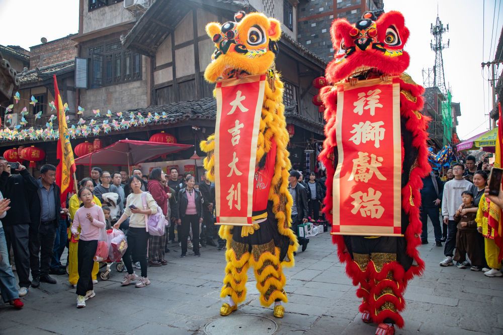 2月20日,游客在四川省宜宾市叙州区横江古镇举办的游龙巡演活动现场观看祥狮献瑞表演。