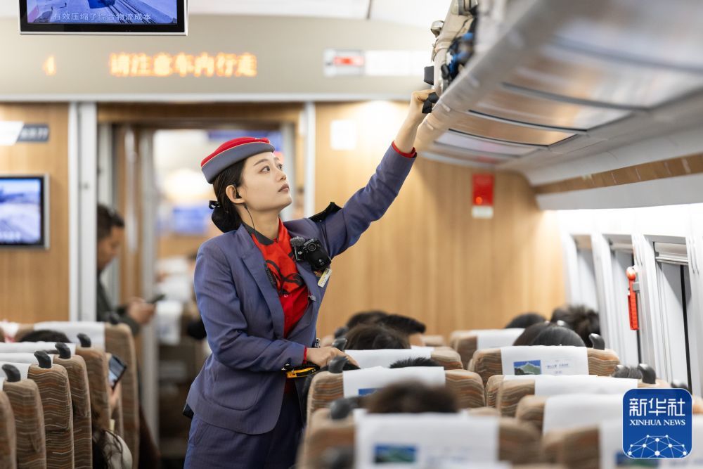 ↑ 5月2日，中国铁路西安局集团有限公司西安客运段列车长在值乘西安北至成都东D1917次动车组列车途中整理行李架。新华社发（刘翔 摄）