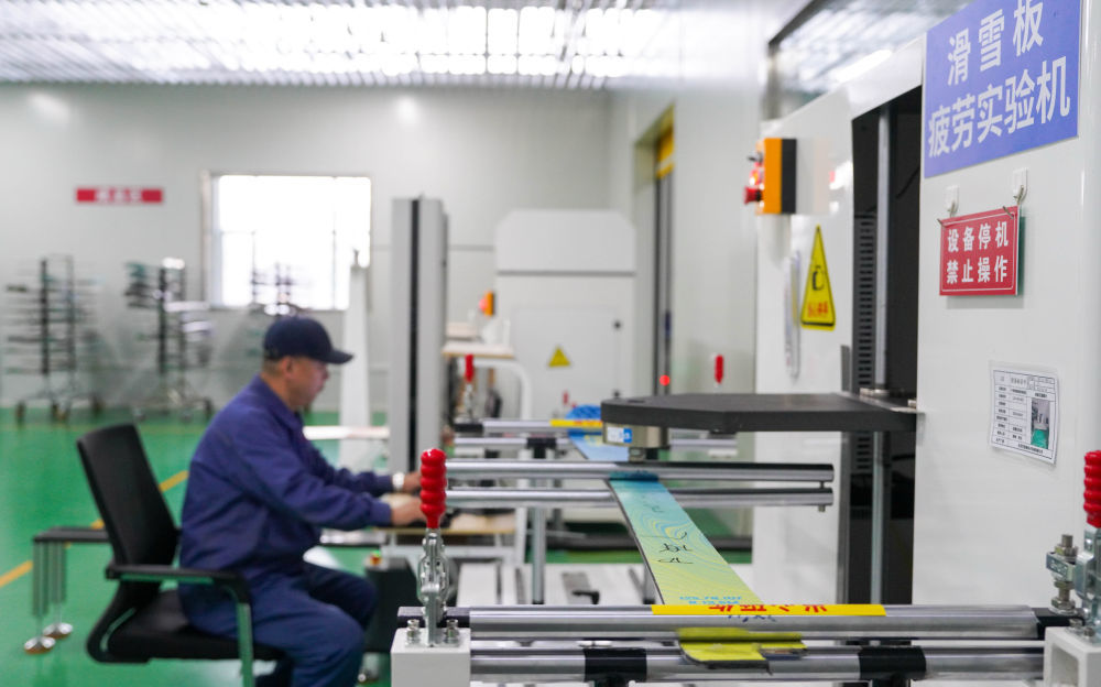 2025年12月4日,在吉林化纤国兴复合材料有限公司的车间内,工作人员用机器设备检测公司自主研发生产的碳纤维滑雪板。新华社记者 颜麟蕴 摄