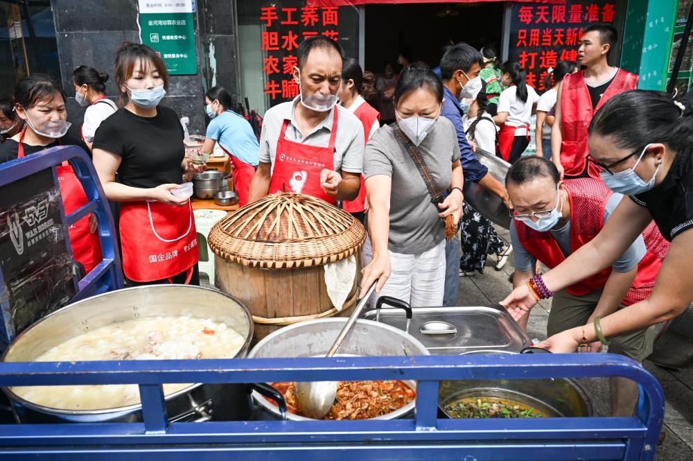 7月19日,在重庆彭水县山体崩塌救援现场附近的一处“爱心食堂”,志愿者准备将做好的午餐送往救援一线。