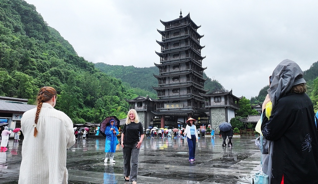 19日，湖南省张家界市，国际搭客在雨中游览张家界国度丛林公园。（视觉中国）