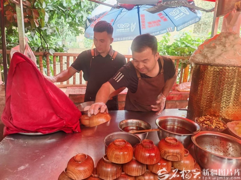 村民胡吉木&middot;吾吉阿布都拉（左）在给游客制作刨冰。石榴云/新疆日报记者 甘兴华摄