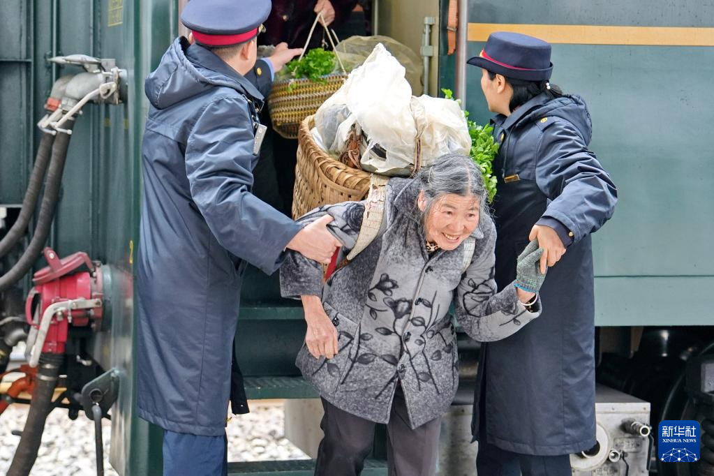 2月25日,在遵义市,5630次列车到达桐梓站后,铁路工作人员协助村民下车。新华社发(张维 摄)