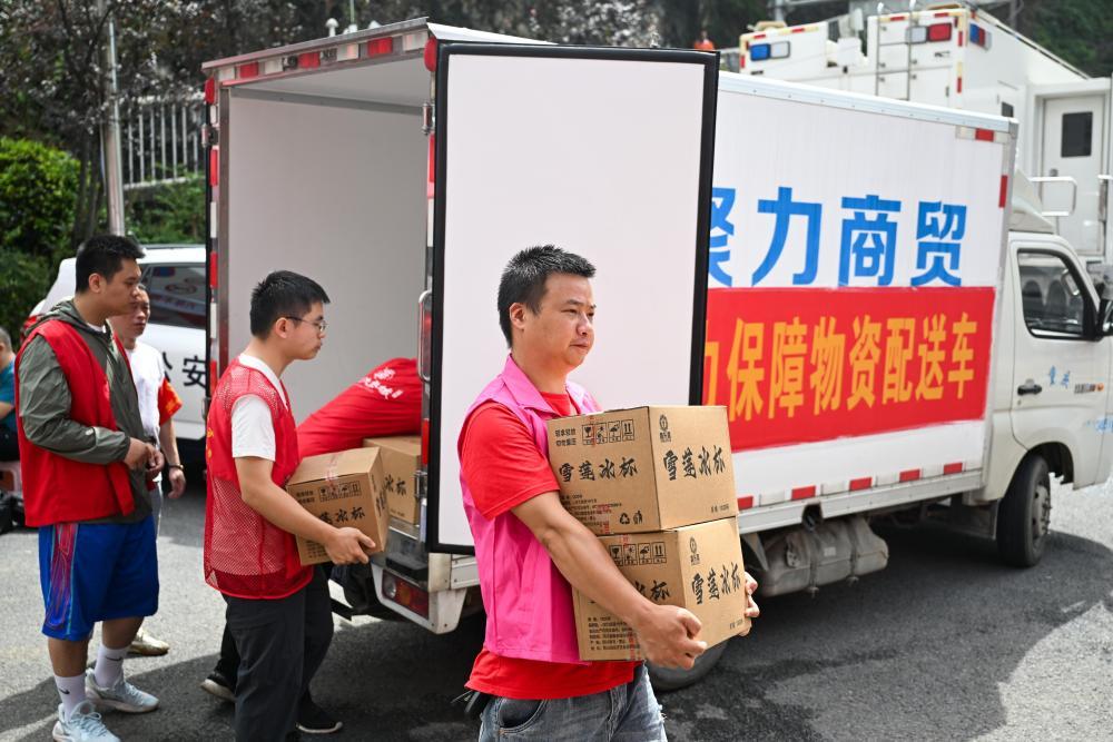 7月19日,志愿者在重庆彭水县山体崩塌救援现场附近搬运物资。
