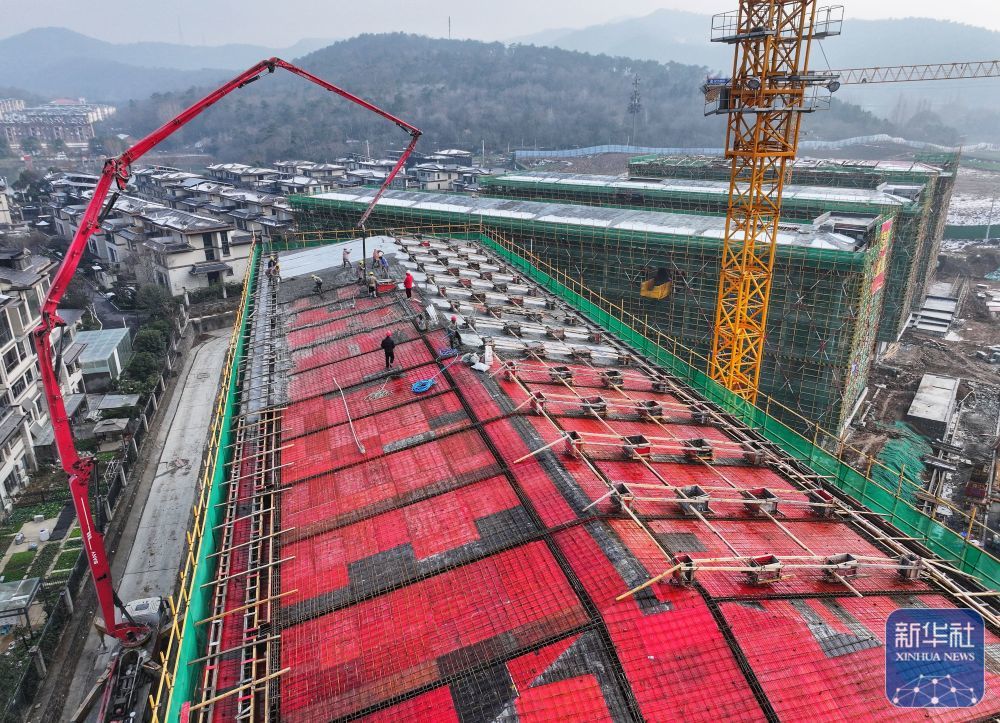 ↑ 1月2日,工人在湖北省襄阳市麒麟中学建设项目工地浇筑屋面水泥(无人机照片)。新华社发(谢勇摄)