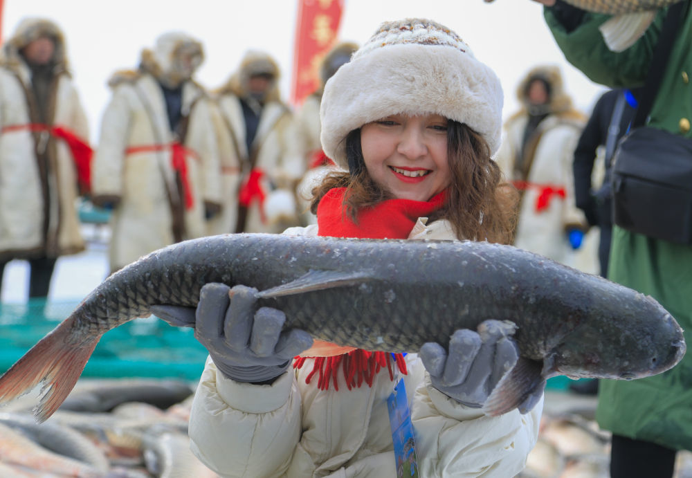 1月18日，在博斯腾湖冰面上，游客手捧刚打捞上来的博斯腾湖鱼。新华社发（年磊摄）