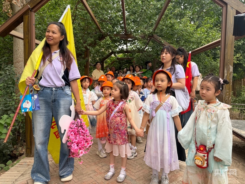 孩子们在葡萄架下认真聆听魏东讲解 （央广网记者 丁安 摄）