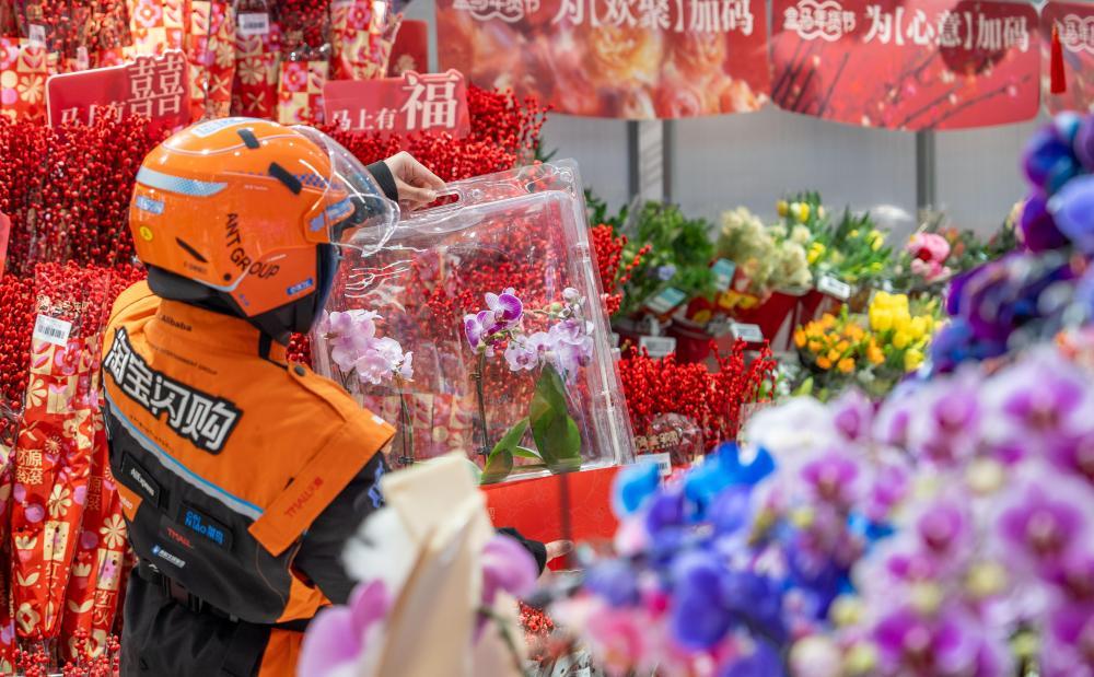 一名外卖骑手正在超市为顾客取春节花卉订单。新华社发