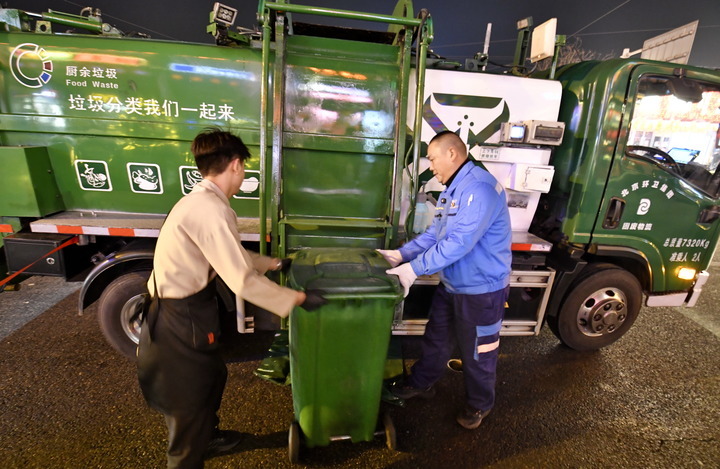 2月4日，北京环卫集团固废物流公司餐厨垃圾清运车司机李宁（右）在帮助饭店员工清运垃圾。新华每日电讯记者李欣 摄