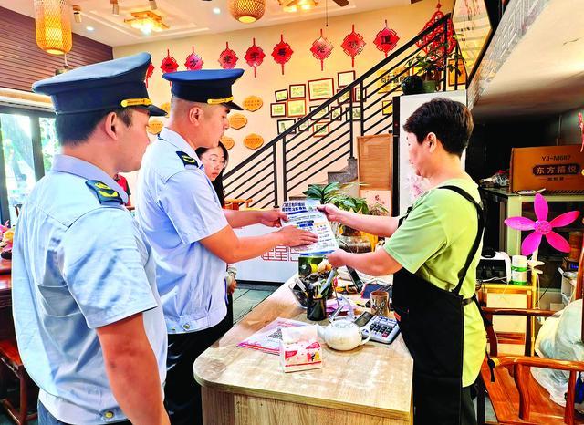 惠城区桥西街道执法人员向餐饮店主宣传“门前三包”。惠州日报记者彭红霞 摄