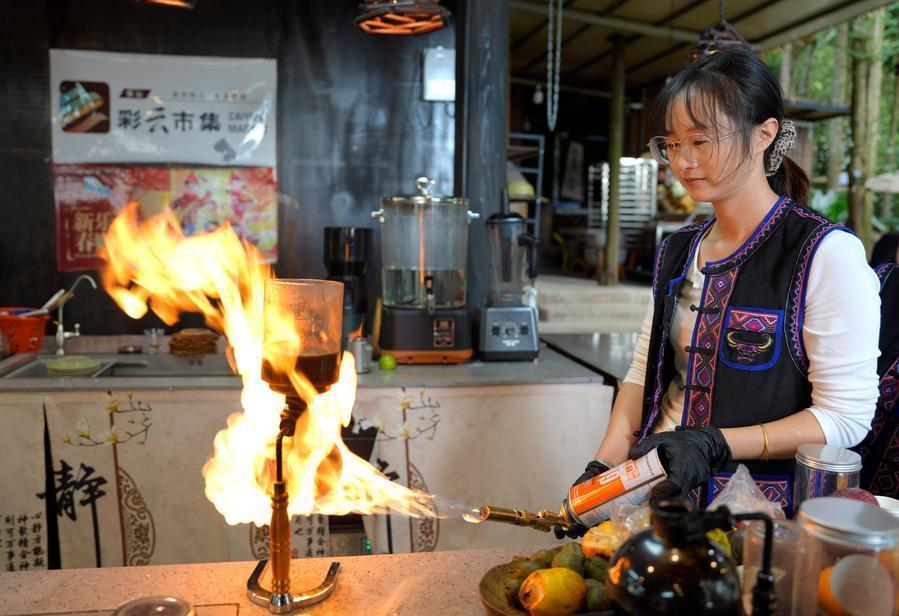 10月19日,工作人员在腾冲市清水镇三家村中寨司莫拉佤族村一家咖啡店内制作火烧咖啡。