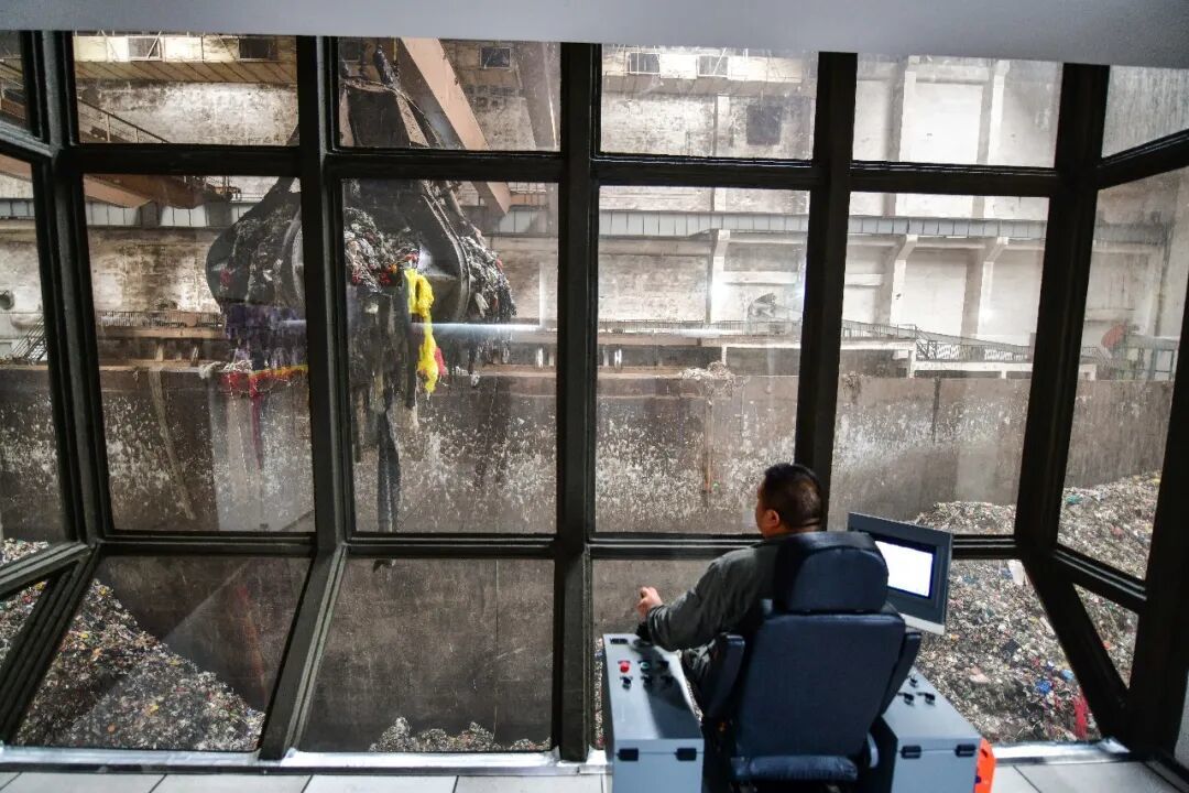 2024年9月19日,在山东启迪济能环保科技有限公司,工作人员在控制室内操作设备吊运垃圾/新华社记者 朱峥 摄