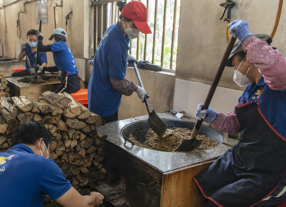 ↑1月11日,海南省琼海市嘉积镇温泉村一家作坊工作人员在翻炒山柚籽粉。新华社发(蒙钟德摄)