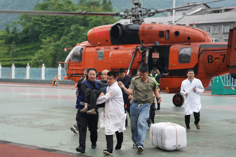 5月21日,人们在石门县南北镇中心学校帮助转移受灾群众。新华社记者 薛宇舸 摄